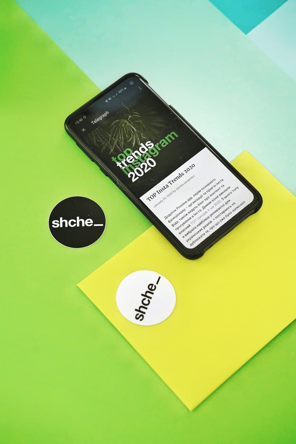 Smartfon wyświetla trendy w mediach społecznościowych obok dwóch naklejek z markami.